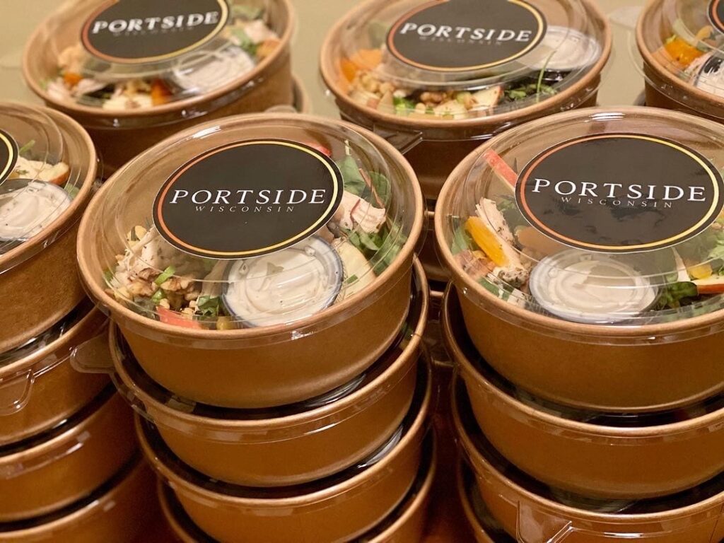 Stacked Portside Catering containers with branded lids, packed and ready for delivery