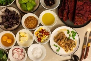 Spread of small bowls with spices, olives, cured meats, dips and soft-boiled eggs