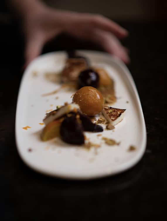 Hand setting down a plate of roasted beets and figs