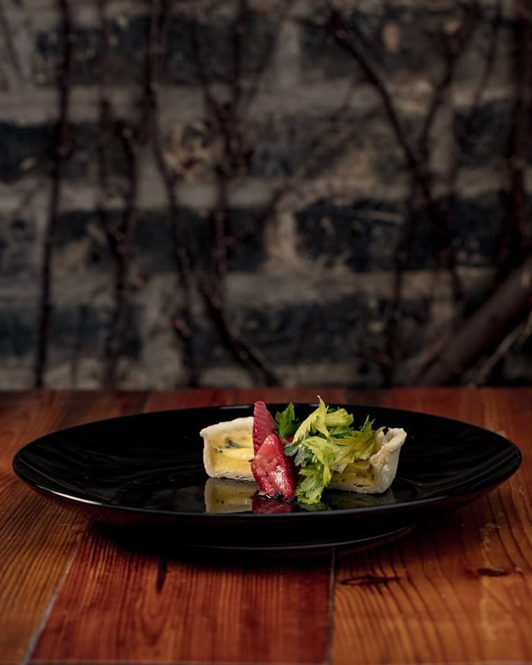 Plated appetizer on a black plate on a wooden table