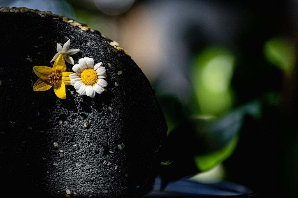 Squid ink bun topped with an edible daisy