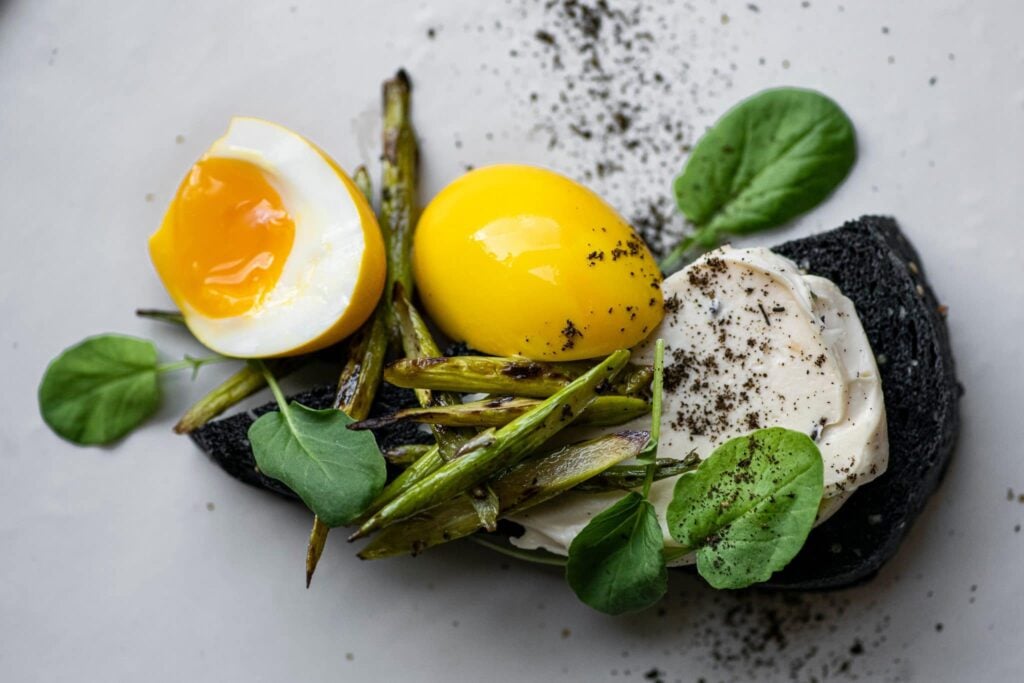 Soft egg, cured yolk, green beans and burrata on squid ink toast
