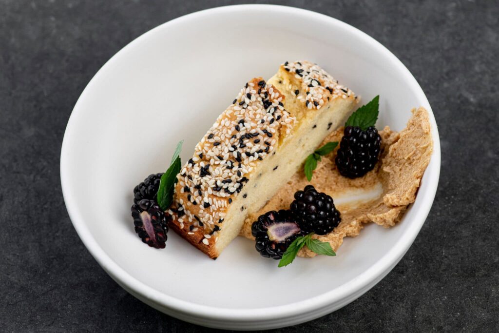 Sesame-crusted terrine with blackberries and purée in a white bowl