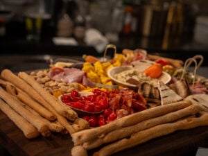Grazing board with breadsticks, cured meats, roasted peppers, olives and dips