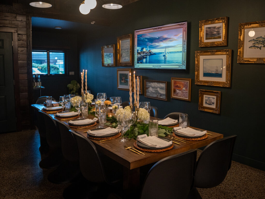 Private dining room set for a long table dinner with candles, greenery and framed artwork